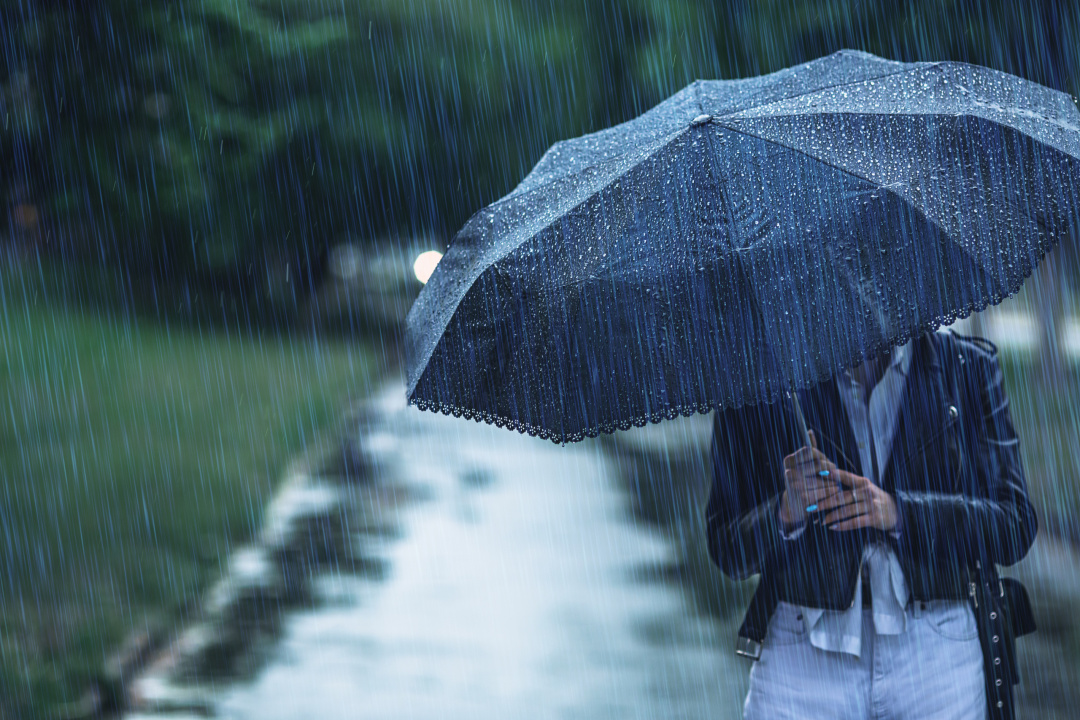 person som går med paraply i regn.