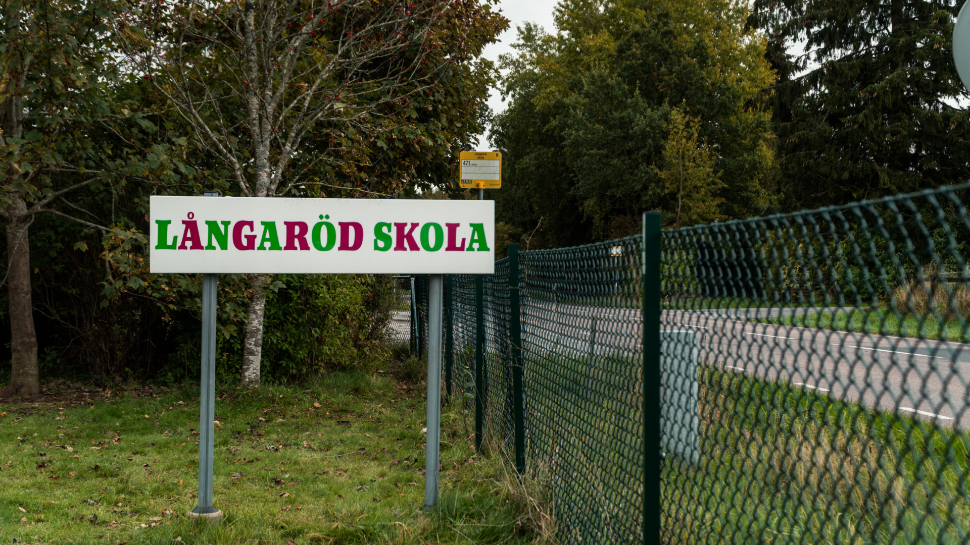 En skylt intill ett staket och en väg med texten: Långaröds skola.