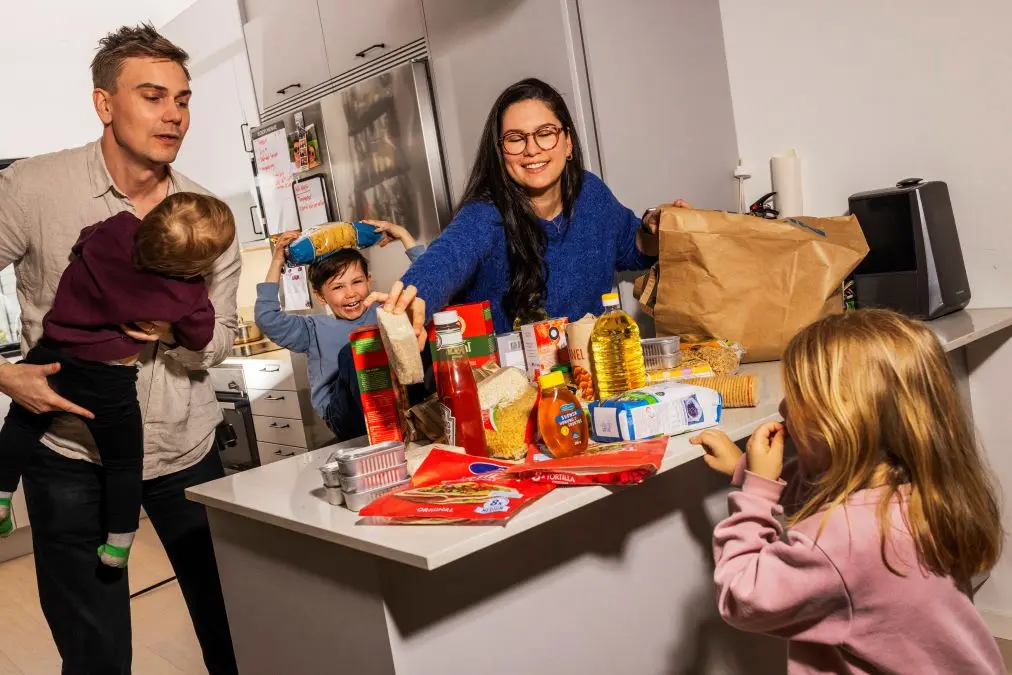 vuxna och barn står i ett kök med matvaror uppradade på diskbänken