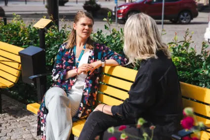 två kvinnor sitter på gul bänk