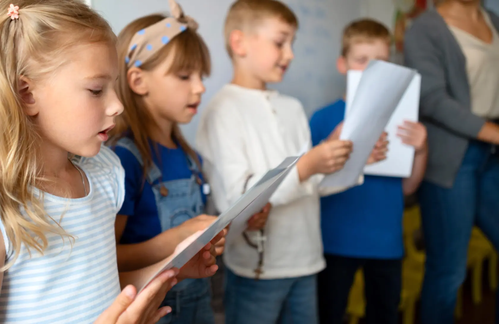 fyra barn står på rad och sjunger från ett papper de håller i handen