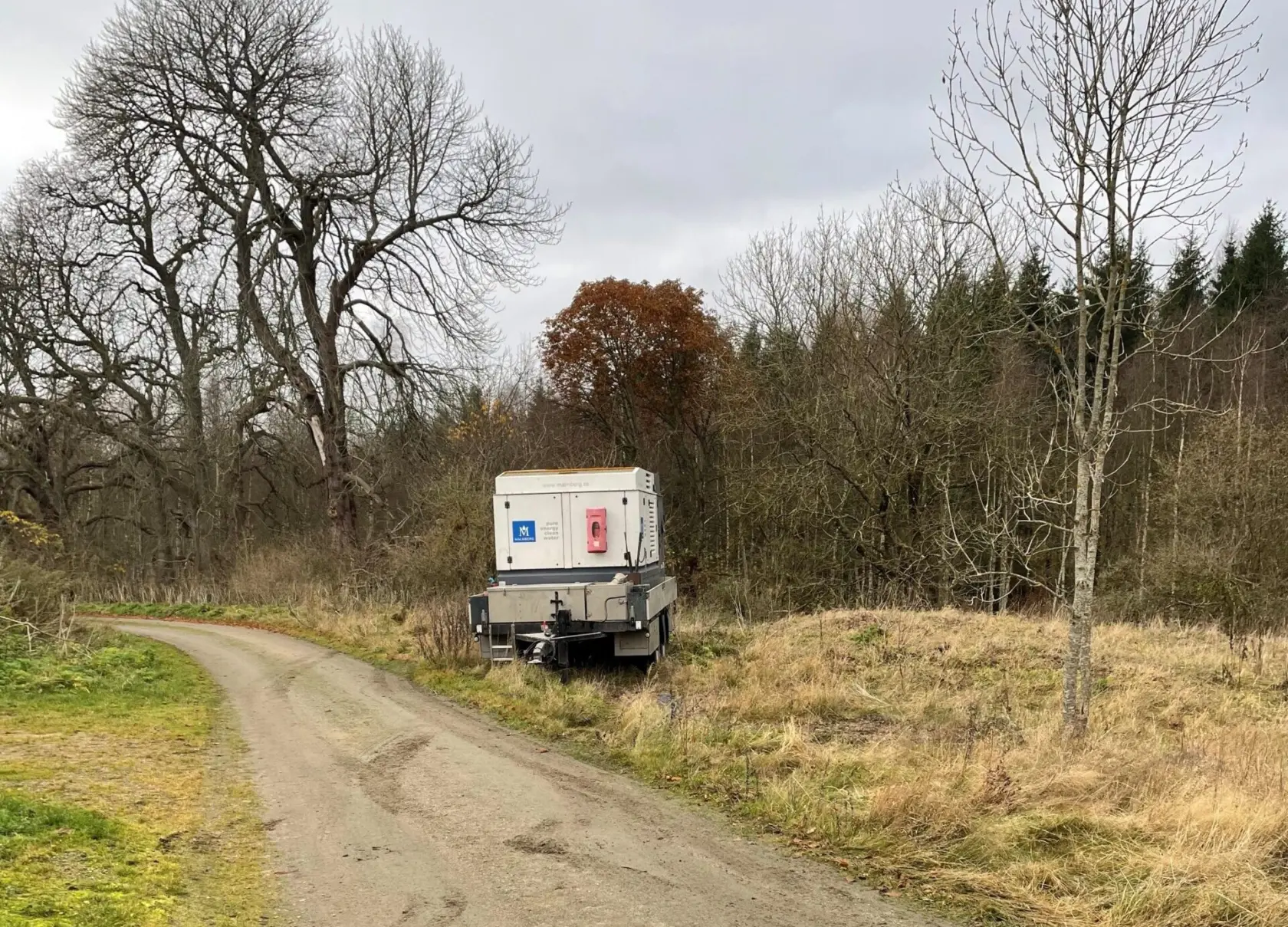 Grusväg i ett skogsbryn med en vagn stående i vägkanten