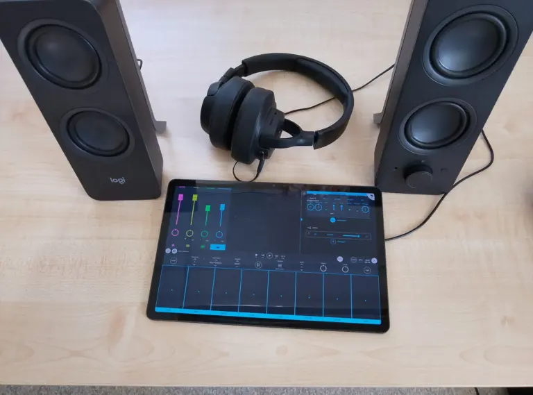 högtalare, headset och en iPad med ett digitalt mixerbord på skärmen