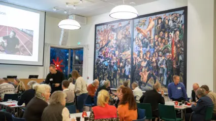 flera människor sitter samlade i en stor sal.
