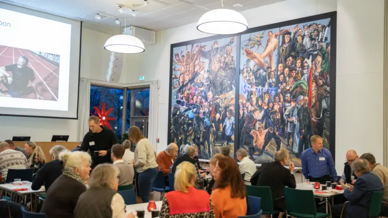 flera människor sitter samlade i en stor sal.
