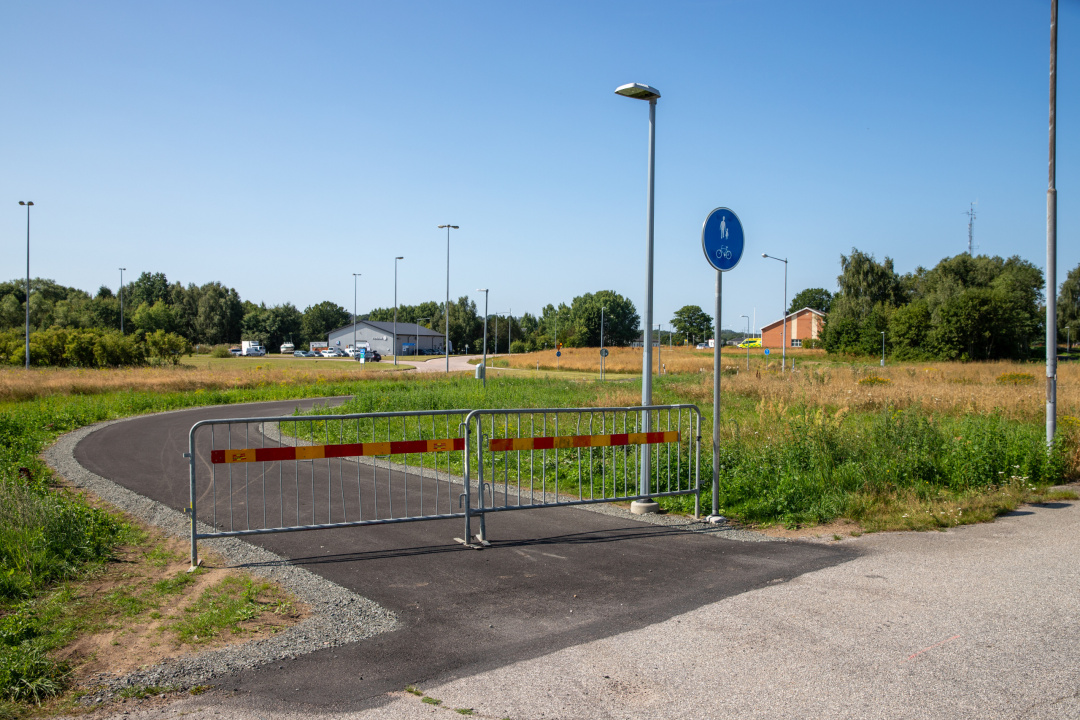 staket vid en asfalterad gång skyltad med gång- och cykelväg.