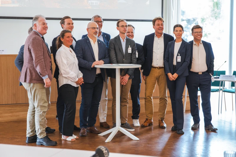 En grupp människor står ihop och tittar in i en kamera.