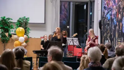 Ungdomar i en popensemble uppträder framför publik.