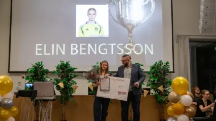 Ung tjej står på ett podie och fåt motta en utmärkelse av en man.