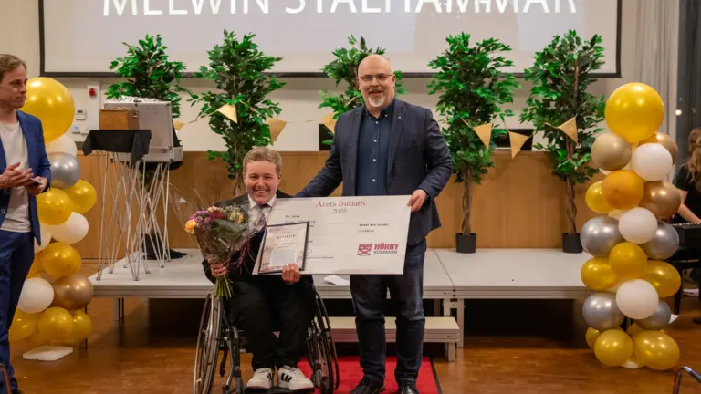 Ung man i rullstol som får ta emot pris av en man.