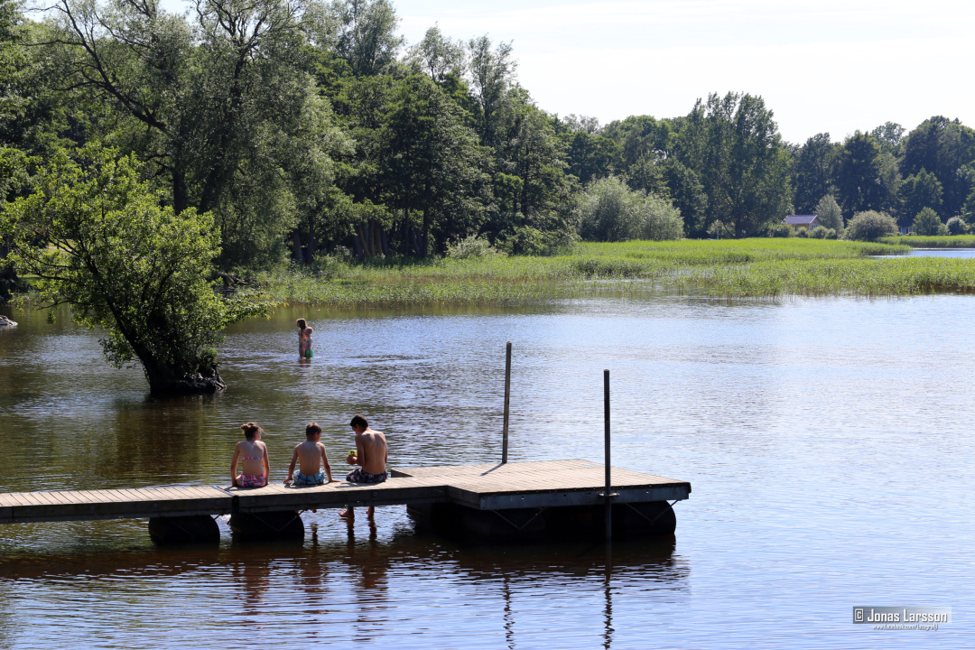 barn som sitter på en brygga vid en sjö