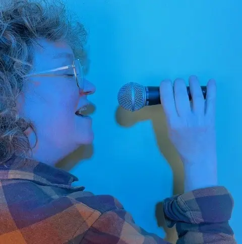 Närbild på kvinna som sjunger in i en mikrofon