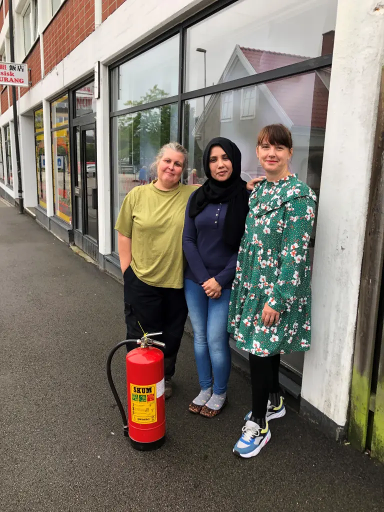 Tre kvinnor fönster skylt brandsläckare på marken