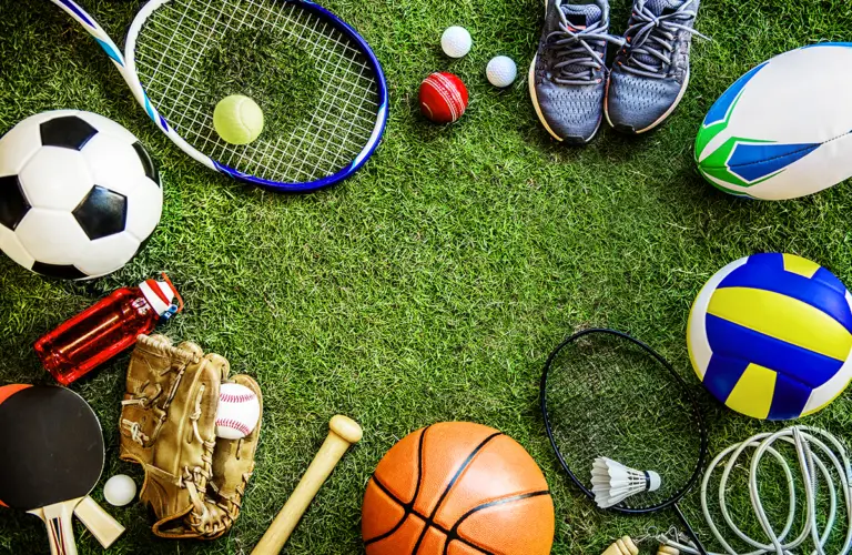 Sportredskap från olika sporter på en gräsmatta.