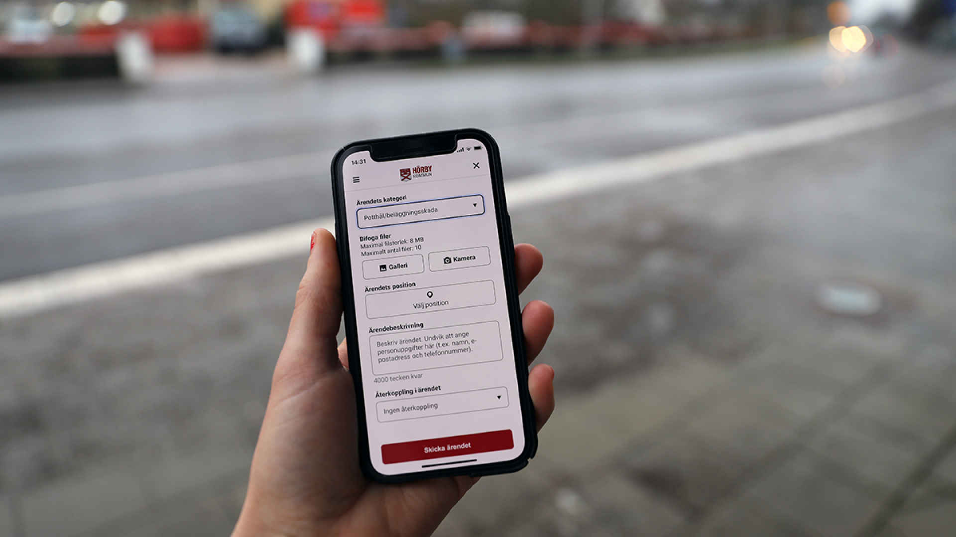 Hand håller en smartphone med appen Tipsa Hörby på skärmen.