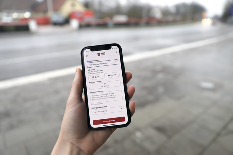 Mobiltelefon i en hand, Hörby-appen synlig