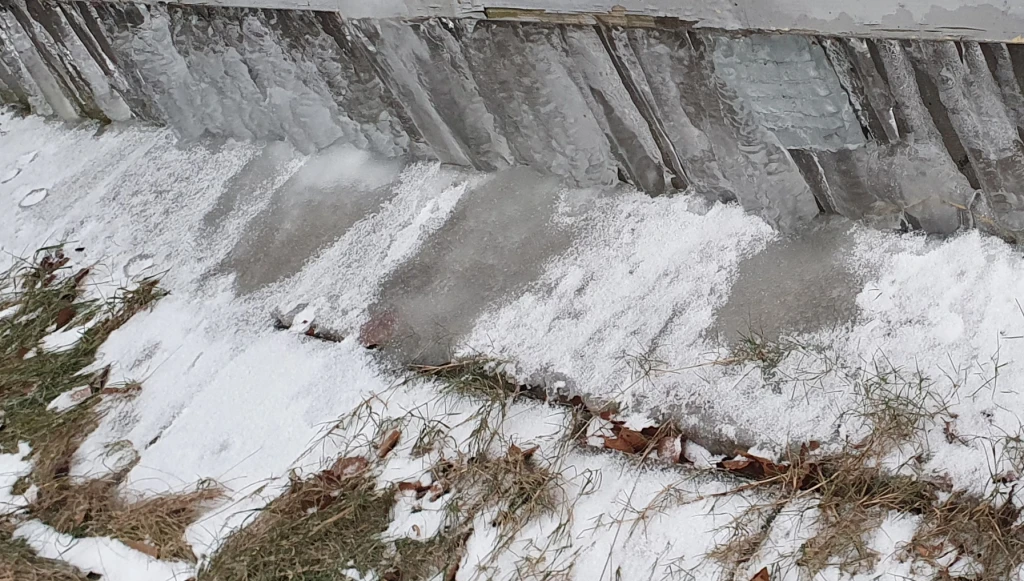 vatten som runnit ner och frusit till is längs en stenmur.