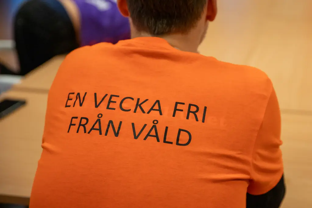 En bild på en ryggtavla som har på sig en orange t-shirt med texten "En vecka fri från våld" tryckt