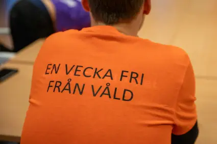 En bild på en ryggtavla som har på sig en orange t-shirt med texten "En vecka fri från våld" tryckt